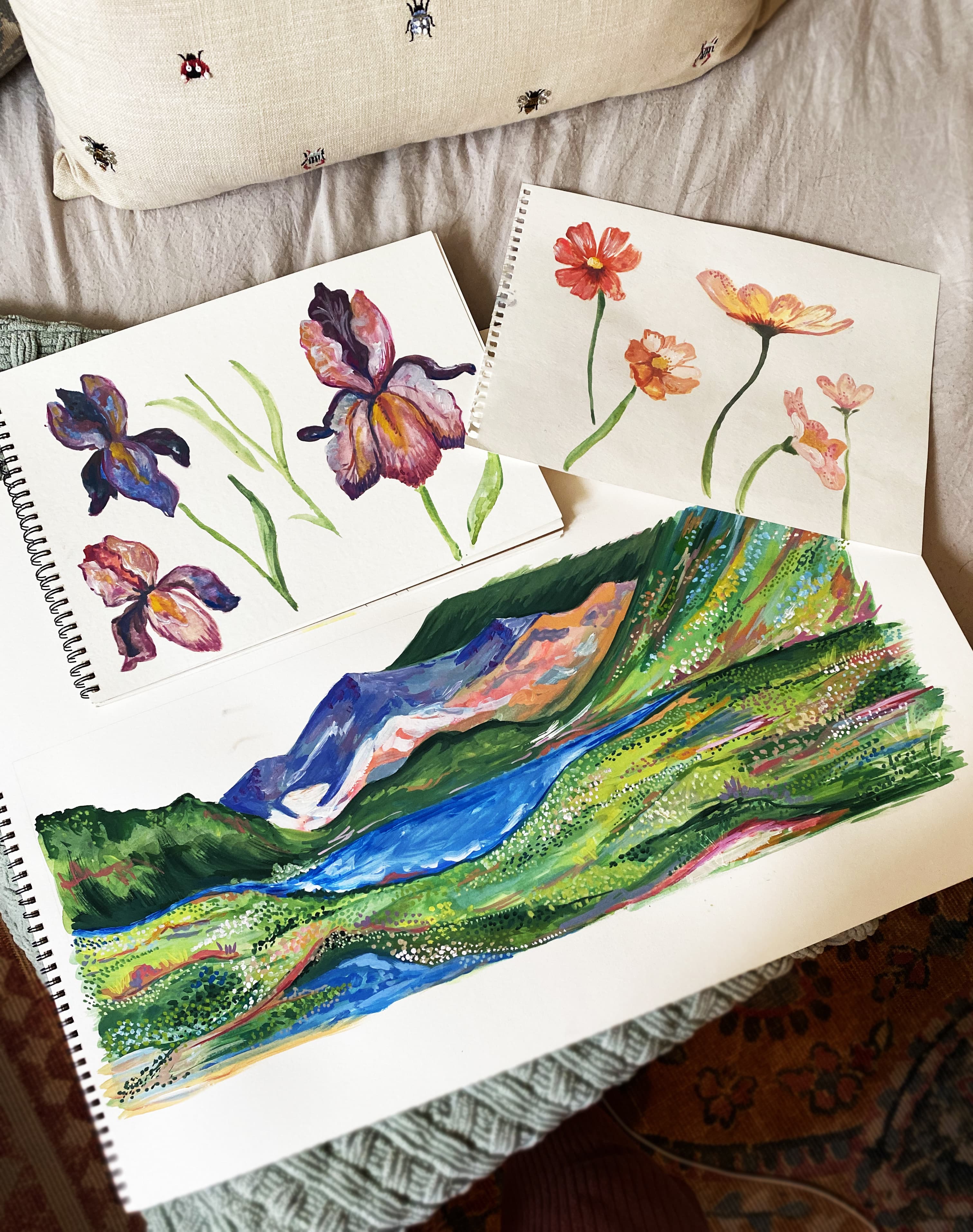 Sketchbooks and paintings spread across the studio table